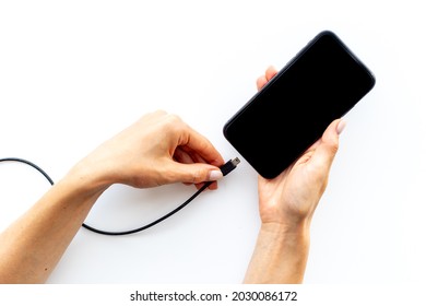 Hands plugging charger in mobile phone. Charging cable for smartphone