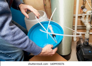 Hands Of A Plumber Hold A Round Lid On Which Lies The Suction Filter Of The Water Of The Osmosis Water Treatment System And Plastic Hoses
