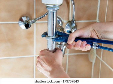 hands of a plumber with sink and wrench