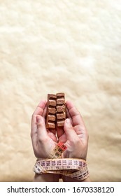 Hands Of Plus Size Woman Tied With Measuring Tape And Holding Chocolate. Weight Loss Problems. Plus Size Woman Cant Stop Unhealthy Eating