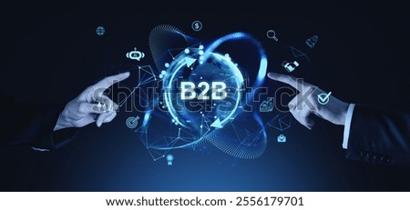 Hands pointing at B2B text with digital icons and network graphics, glowing in blue tones on a dark background, representing business technology