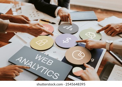 Hands pointing at web analytics icons on a table. Web analytics tools and data visualization. Diverse Collaborative business meeting on web analytics strategy. - Powered by Shutterstock