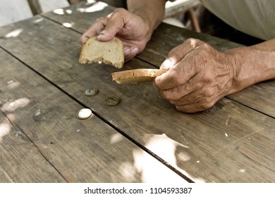 Hands the poor old man's, piece of bread and change, pennies on wood background. The concept of hunger or poverty. Selective focus. Poverty in retirement.Homeless. - Shutterstock ID 1104593387