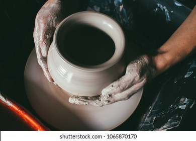 hands of a potter, creating an earthen jar on the circle. Potter at work. Top view of potter clay preparation for manufacturing making ceramic pot on the pottery wheel