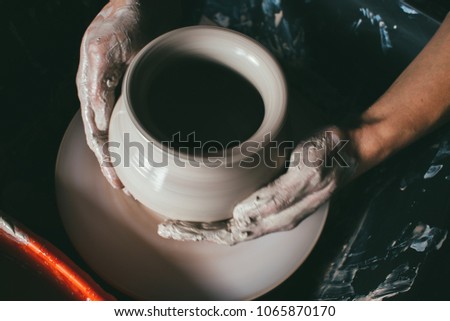 hands of a potter, creating an earthen jar on the circle. Potter at work. Top view of potter clay preparation for manufacturing making ceramic pot on the pottery wheel