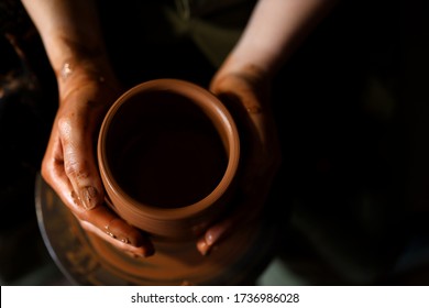 Hands of potter do a clay pot.The view from the top. A Potter sculpts his hands with a clay Cup on a Potter's wheel. Close. Soft focus. Shooting in the dark key. Space for text - Powered by Shutterstock