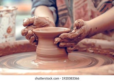 Hands of a potter at work. Potter making ceramic mug on the pottery wheel