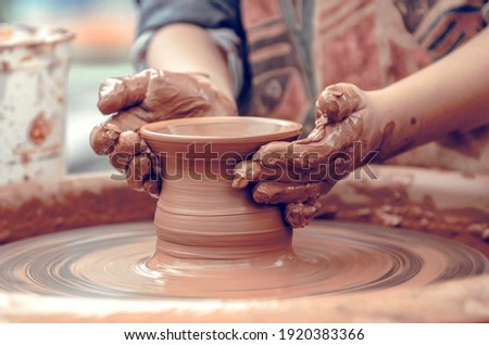 Hands of a potter at work. Potter making ceramic mug on the pottery wheel