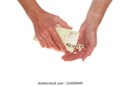 Hands Pouring Seeds From A Packet Isolated Against White