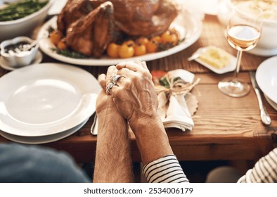 Hands, pray and food with a senior couple sitting at a dining room table for a roast lunch together. Prayer, grace and holding hands with a mature man and woman eating, bonding or enjoying a meal - Powered by Shutterstock