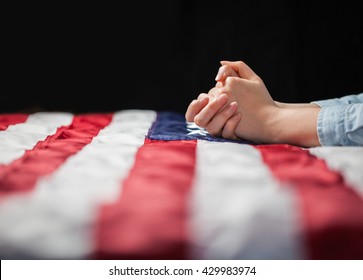 Hands praying over american flag