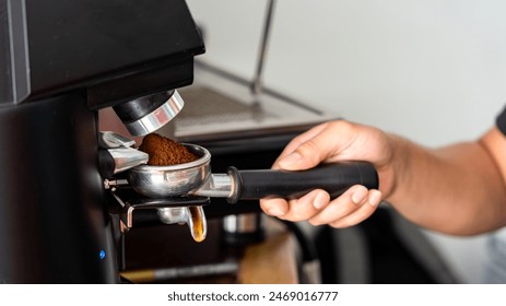 Artisan’s hands prepare ground coffee for a perfect shot. The texture of the freshly ground beans and the stainless steel create an authentic coffee scene - Powered by Shutterstock