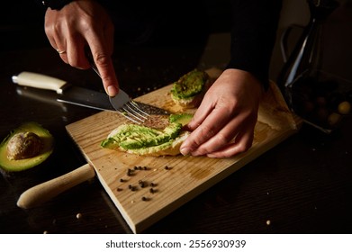 Hands preparing avocado toast on a cutting board, highlighting fresh ingredients and culinary skills in the kitchen. - Powered by Shutterstock