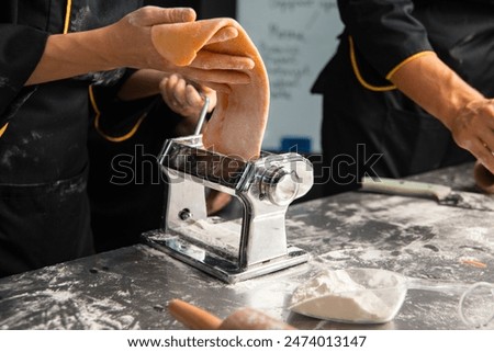 Hands preparing fresh pasta with a pasta machine, showcasing the art of homemade Italian cuisine