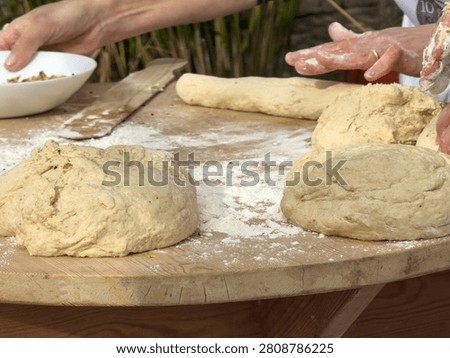 Hands preparing traditional Cretan bread dough on a rustic wooden table scattered with flour during an authentic baking workshop.