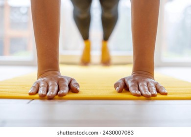 Hands pressed flat on yellow yoga mat, workout session indoors