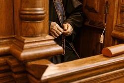 Hands Of A Priest Holding A Catholic Rosary During Confession In The Confessional