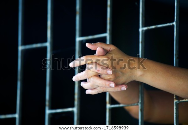 hands of prisoner in jail\
background.