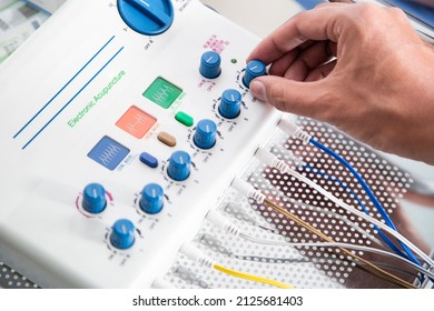 
hands of a professional in alternative medicine, electric acupuncture machine
