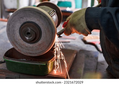 Hands of Professional Fitter Man Using Metal Polishing Machine for Metal Rods Sharpening With Sparks in Workshop. Horizontal Image Orientation - Powered by Shutterstock