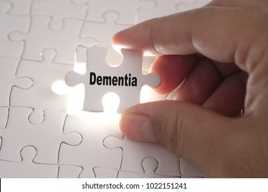 Hands of Professor Doctor holding a jigsaw puzzle with Dementia word. Medical concept.