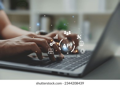 Hands of programmer and laptop with API or Application Program Interface, smart phone and online application concept. - Shutterstock ID 2344208439