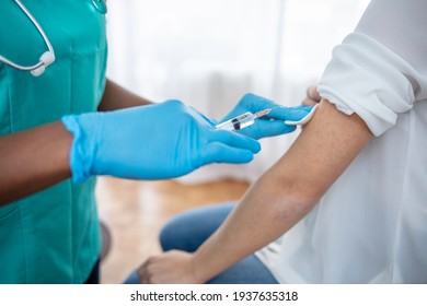 Die Hände mit Schutzhandschuhen füllen die Spritze mit Impfstoff. Hände des Arztes in Handschuhen, die einem Patienten Impfstoff injizieren. Arzt, der Frauen muskulär injiziert. Konzept der Impfung