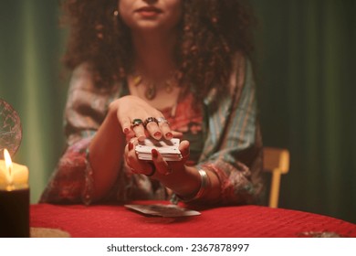 Hands of psychic shuffling tarot cards before spreading on table