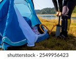 Hands pumping the air mattress in the tent and preparing everything for the night.