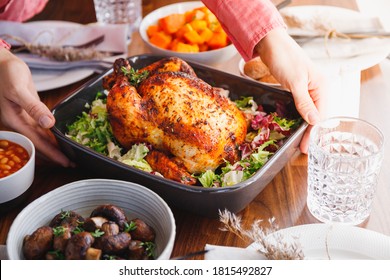 Hands Put A Dish With Whole Roasted Chicken On A Festive Table. The Concept Of Family Dinner Or Thanksgiving Celebrate