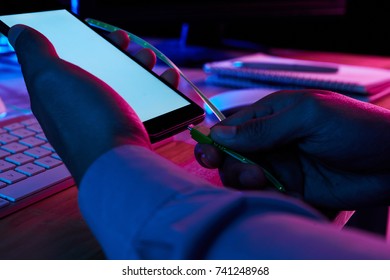 Hands of hands putting mini USB cable into smartphone connector