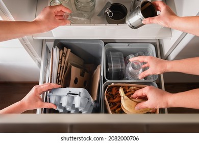 Hands putting segregated household garbage to separate trash bins - plastic, cardboard, bio, metal and glass. - Shutterstock ID 2082000706