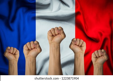 Hands Raised Up And Clenched Into A Fist Against The Background Of The Flag Of France. Concept Of The Unity Of The French People, Revolution, Revival, Riot