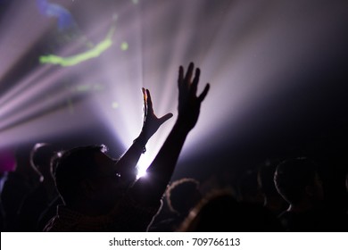 Hands raised in excitement and praise at contemporary church concert and bright lights