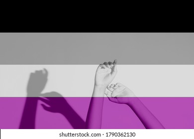Hands raised freely with shadow behind, in colors of Asexuality flag. Acceptance, freedom, sexual orientation, lgbtq pride