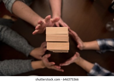 Hands Reach Out To Steady A Pile Of Blocks To Keep It From Tumbling During A Game.