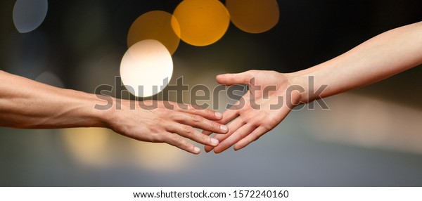 Hands reaching out and touching each other on\
a dark background
