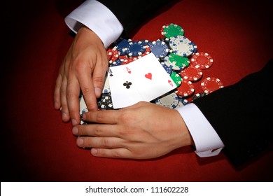 Hands Reaching For Poker Chips On Red Background