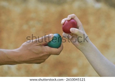Hands with red Easter eggs knocking.  Ready for egg tapping. Happy Easter!