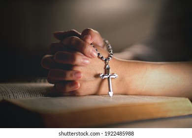hands of religious christian woman holding jusus cross rosary praying to god with holy bibble book in chruch