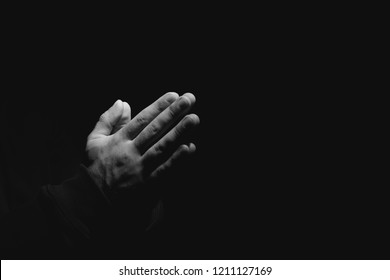 Hands of religious man praying on dark background, black and white effect