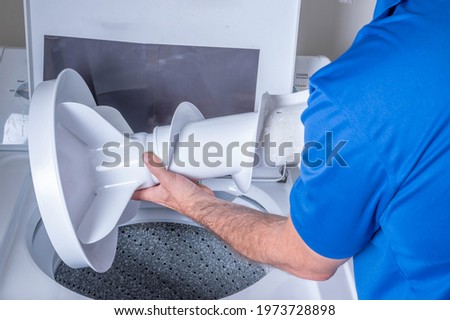 Hands removing or installing a agitator from a broken washing machine