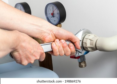 Hands repairing valves in boiler room, closeup