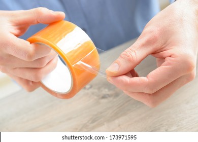 Hands With Roll Of Transparent Packaging, Adhesive Tape.