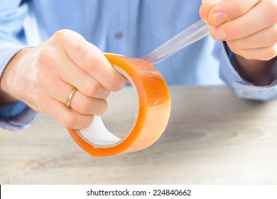 Hands With Roll Of Transparent Packaging, Adhesive Tape.