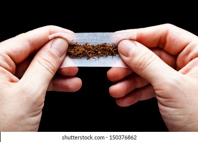 Hands Rolling A Cigarette Paper With Tobacco