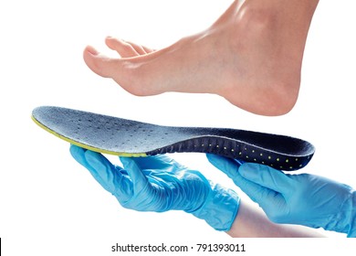 Hands in rubber gloves hold an orthopedic insole
