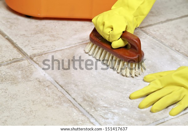 hands in rubber\
gloves scrubbing the\
floor