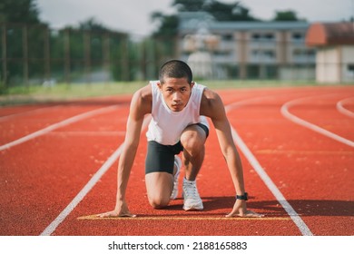 Hands runner ready start to run athlete sportman training run on lane at the stadium in morning. Runner man wearing white vest to practice running prepare for competition race.