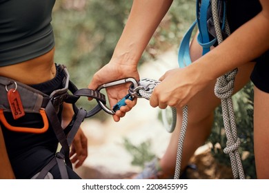 Hands, safety and rock climbing a mountain with a climber securing ropes for abseiling or scaling mountains outdoor in nature for health and fitness. Training, workout and sports with two athletes - Powered by Shutterstock